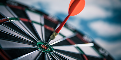 An orange dart hitting bullseye on a target