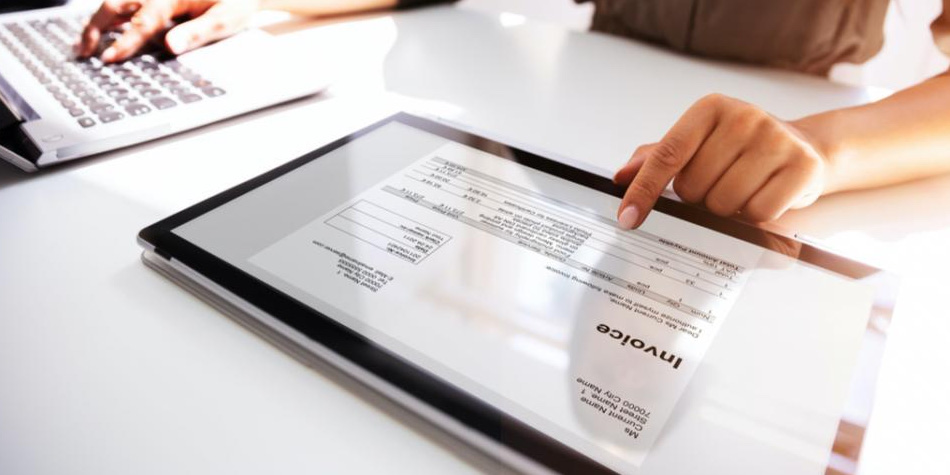 Person viewing an invoice on an tablet and working on laptop