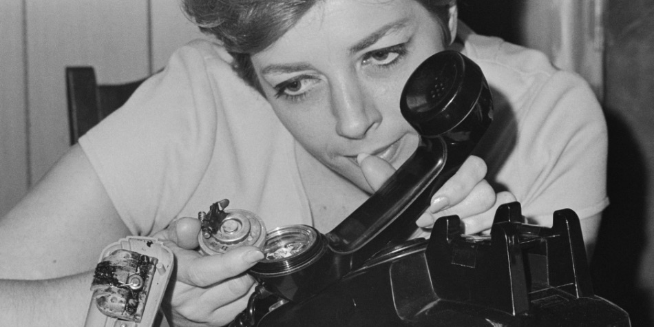 Woman looking at the insides of a phone from the 1960s