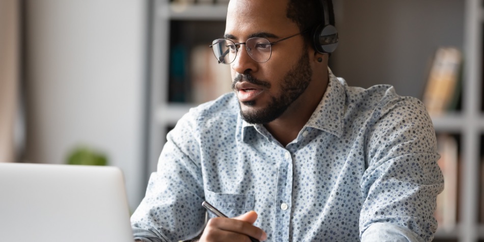 Man with glasses and headset on laptop