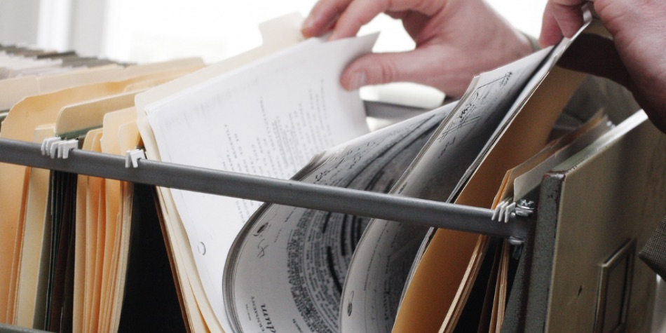 Person's hand looking at files in a file cabinet