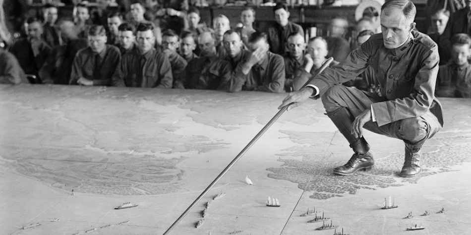 Man standing on map pushing military ships across the sea