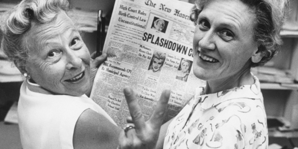 Two women from the 1960s reading a newspaper