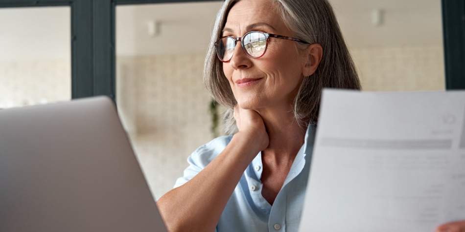 Woman with glasses looking at a report on a laptop