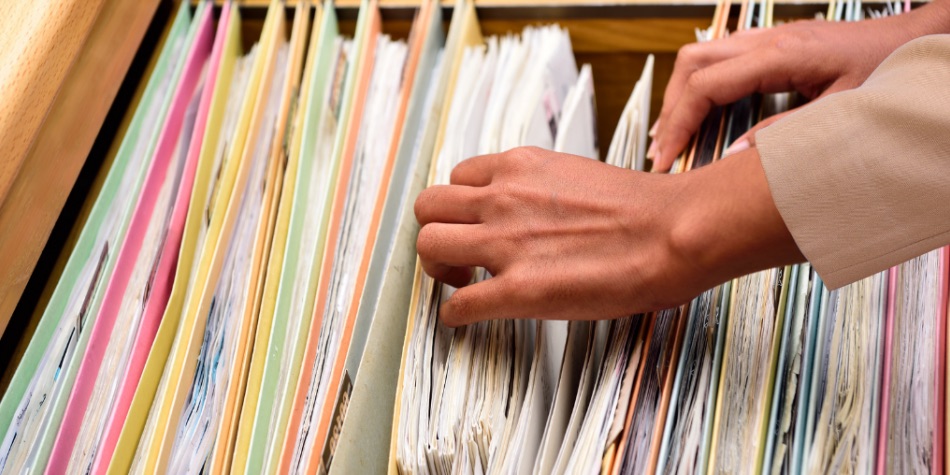 A person's hands going through a file cabinet