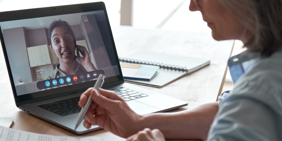 Woman working at a desk communicating with another person via video conferencing