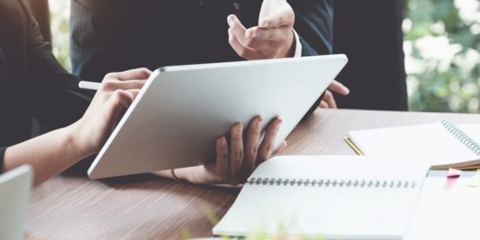 Two people working at a table with a tablet